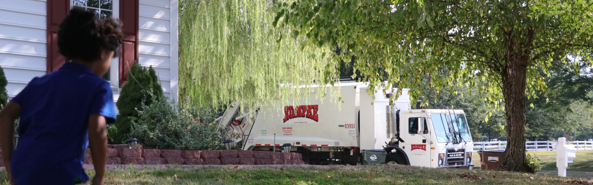 Child Running Toward Rumpke Recycling Truck In Residential Neighborhood